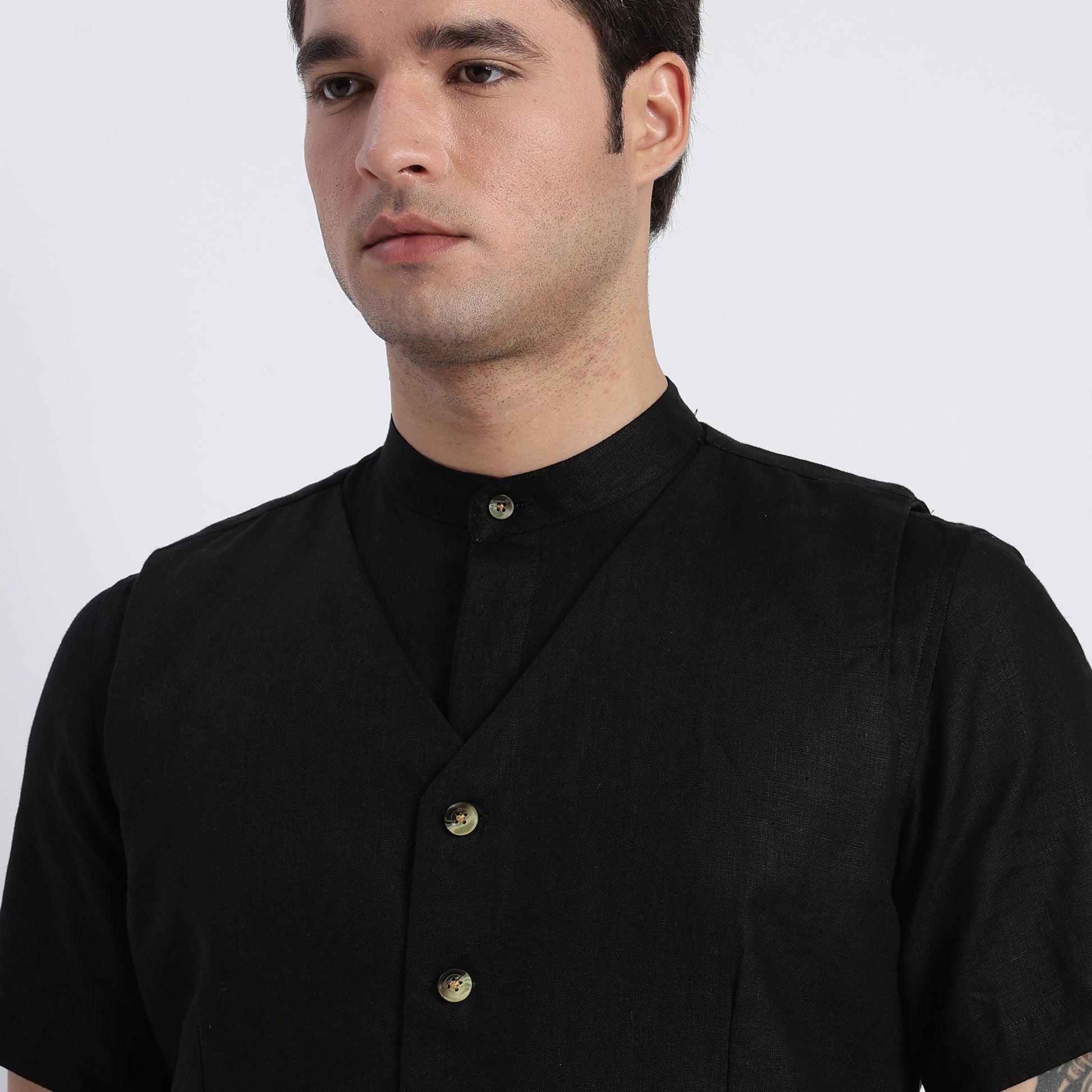 Man wearing a black shirt with buttons on a white background